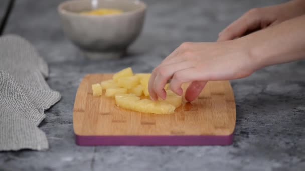 Vrouw handen snijden ananas op kleine stukjes. - Video