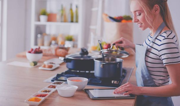 Young woman using a tablet computer to cook in her kitchen - Fotoğraf, Görsel