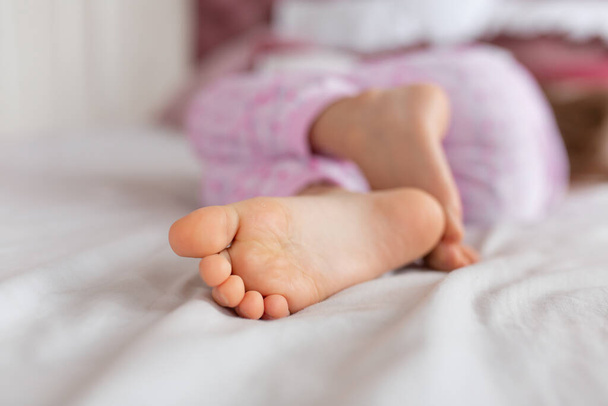 Feet of a girl sleeping in a comfortable bed. Focus on the foot. - Photo, Image