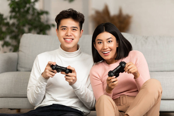 Χαρούμενος Ασιάτης φίλος και φίλη Παίζοντας βιντεοπαιχνίδι στο σπίτι - Φωτογραφία, εικόνα