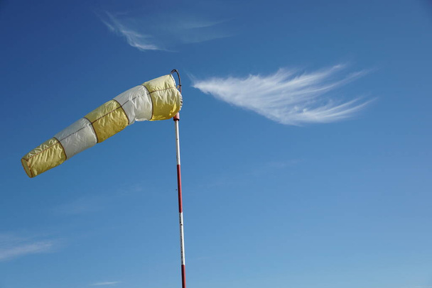 Geel-witte wind sok op de blauwe lucht achtergrond. - Foto, afbeelding
