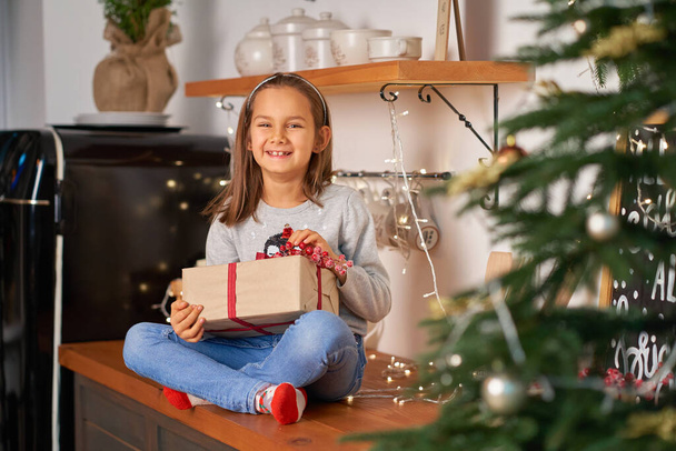 Little girl opens a box with a Christmas present from Santa. - Valokuva, kuva