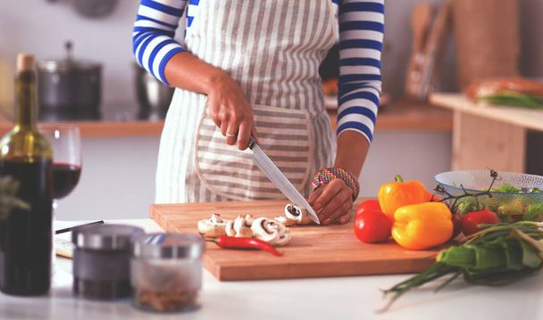 Young woman cutting vegetables in kitchen - Foto, Imagen