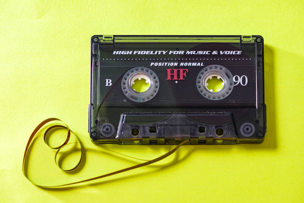 Vista superior del casete de audio con cinta enredada sobre fondo amarillo brillante con espacio de copia, composición minimalista - Foto, Imagen