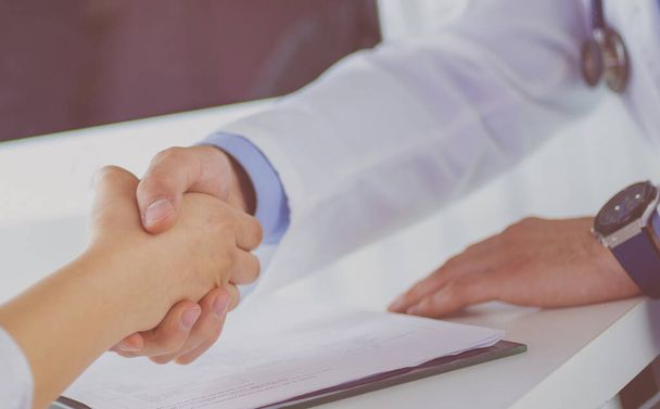 Doctor shaking hands to patient in the office at desk - Φωτογραφία, εικόνα