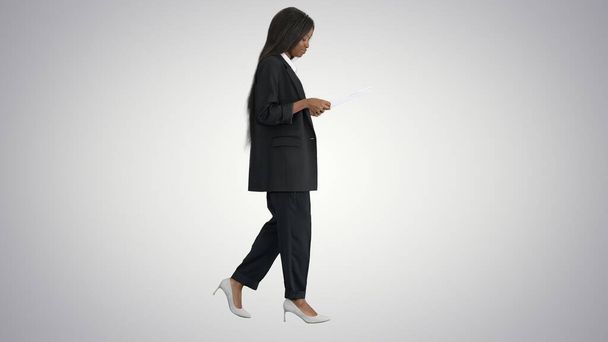 Серьезный африканский американец женщина читает документы во время ходьбы о - Фото, изображение
