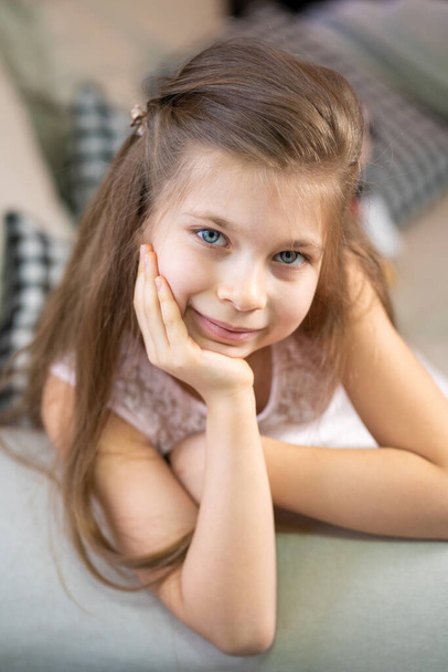 Portrait of a little girl who lies on the sofa, leaning on her arm. - Fotó, kép