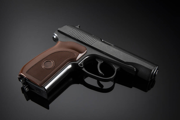 Pistolet noir avec poignée marron sur fond dégradé gris - Photo, image