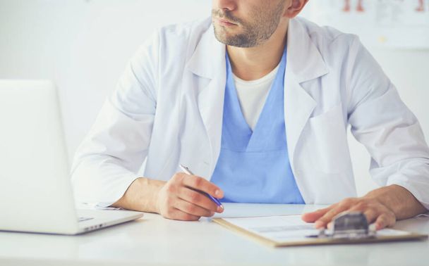 Portret lekarza z laptopem siedzącego przy biurku w gabinecie lekarskim - Zdjęcie, obraz