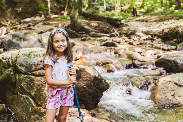 Happy portrait of little girl hiking at mountain stream. summer day in the nature  - Photo, Image