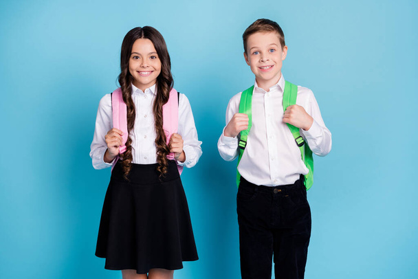 Photo of two little girl boy schoolkid best friends sister brother prepare morning walk to school wear backpack white shirt black pants dress isolated blue color background - Φωτογραφία, εικόνα