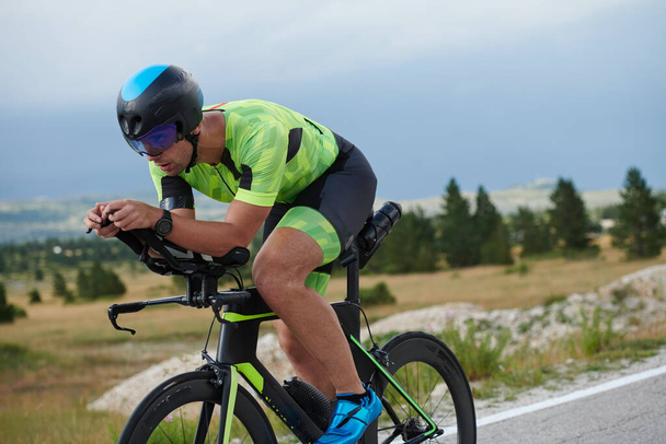 triathlon athlete riding professional racing bike at workout on curvy country road - Fotó, kép