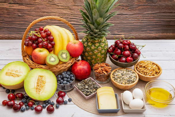 グループナッツボウルに入れて乾燥し、果物はバナナであります,パイナップルとブドウは、木製のテーブルの背景に健康食品です. - 写真・画像