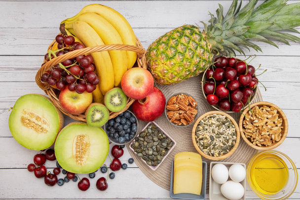 グループナッツをボウルに入れ、果物はバナナ、パイナップルとブドウは木製のテーブルの背景に健康食品です。 - 写真・画像
