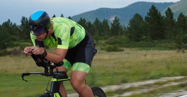 triathlon athlete riding professional racing bike at workout on curvy country road - 写真・画像