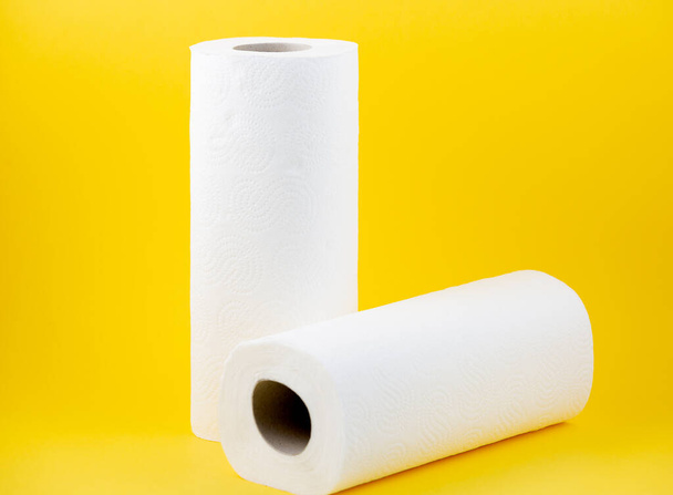 Un rollo de papel higiénico blanco grande para uso en baños o cocinas, utilizado para limpiar la suciedad en el baño sobre fondo amarillo - Foto, imagen