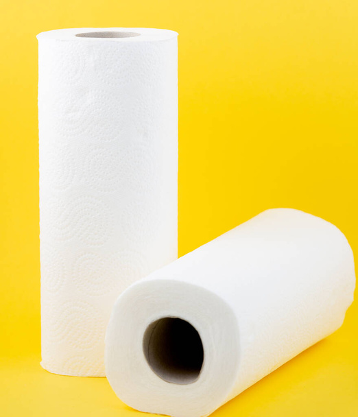 Ένα μεγάλο λευκό ρολό χαρτιού υγείας για χρήση σε μπάνια ή κουζίνες, που χρησιμοποιείται για τον καθαρισμό βρωμιά στο μπάνιο σε κίτρινο φόντο - Φωτογραφία, εικόνα