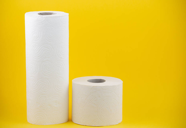 Un grand rouleau de papier toilette blanc pour une utilisation dans les salles de bains ou les cuisines, utilisé pour nettoyer la saleté dans la salle de bains sur fond jaune - Photo, image