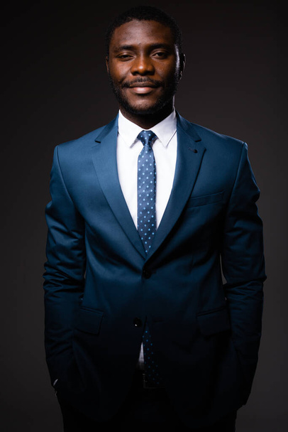 Portrait of an african american businessman man in blue classic suit who stands on gray background - Foto, Imagem