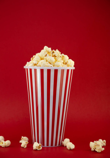 Butterpopcorn in einem roten Popcornbecher, geröstete Buttermaiskerne gemischt mit natürlichem Salz, Vorspeisen im Kino oder auf einer Party - Foto, Bild