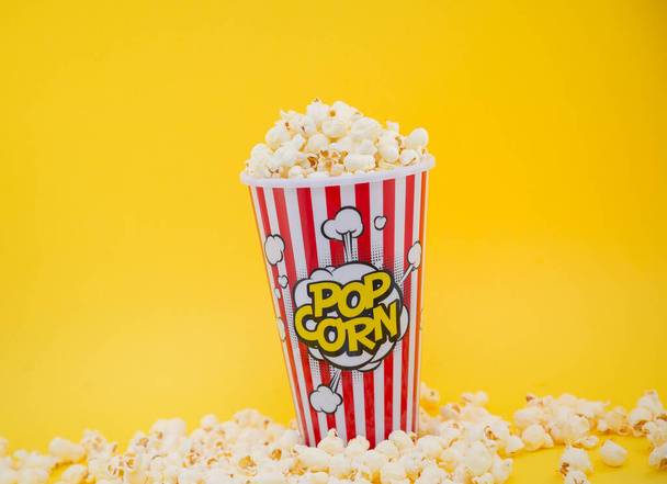Vajas popcorn piros popcorn pohárban, pirított vajas kukoricamagvak természetes sóval keverve, étvágygerjesztők moziban vagy buliban - Fotó, kép