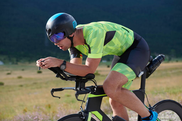 triathlon athlete riding professional racing bike at workout on curvy country road - Fotó, kép