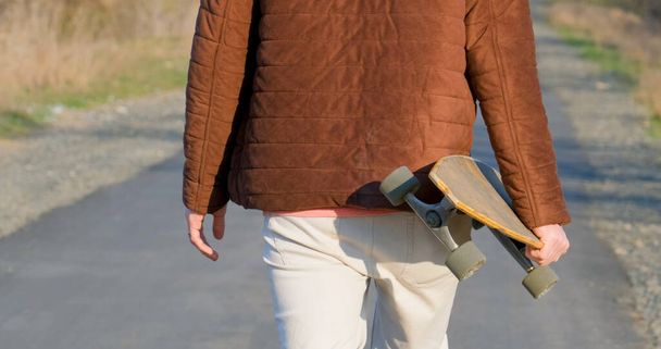 Young male ride on longboard skateboard on the country road in sunny day - 写真・画像