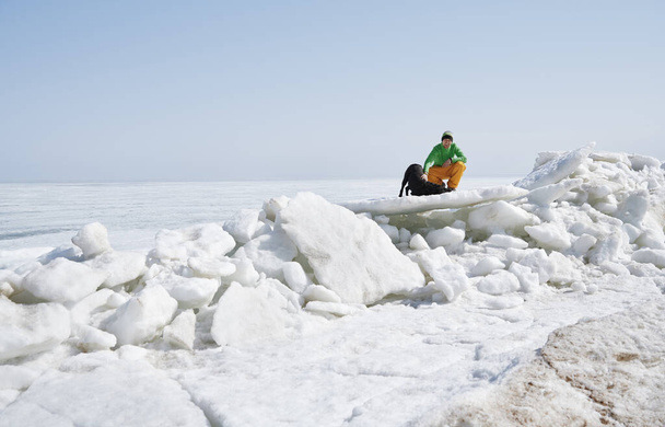 Jonge volwassen man buiten met zijn hond plezier hebben in de winter landschap - Foto, afbeelding