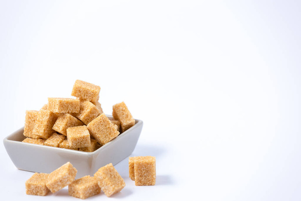 Brown sugar in a square cup on a white background, healthy sugar is used for cooking or desserts. - 写真・画像