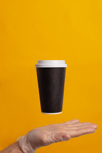 A hand in a glove holds a disposable cup - Fotó, kép
