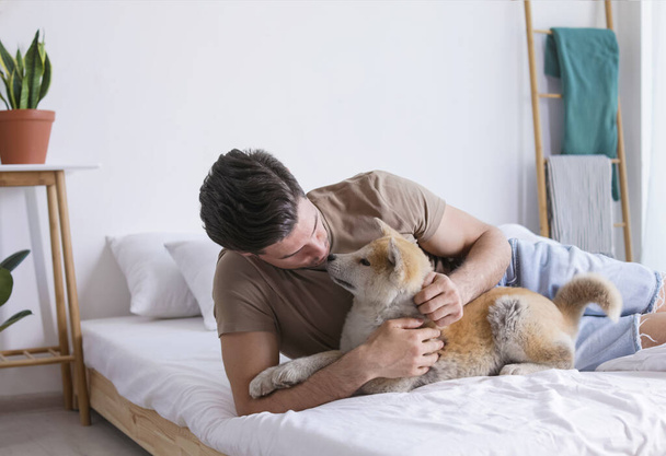 Happy man with his cute Akita Inu puppy at home - Foto, Bild