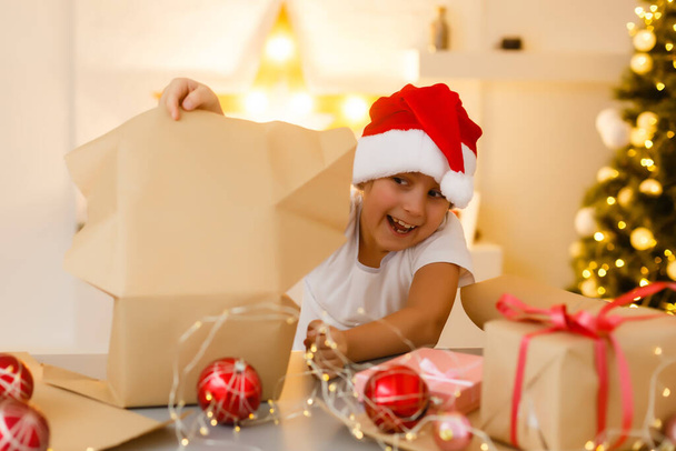 Noel, Noel, Noel, kış, mutluluk konsepti. Noel Baba şapkalı, hediye kutusuyla gülümseyen kız. - Fotoğraf, Görsel