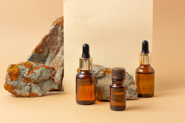 An amber bottle for essential oils and cosmetics stands next to the stone. Glass bottle. Dropper, spray bottle. Natural cosmetics concept. - Fotó, kép