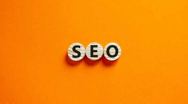 Concept word 'SEO' on wooden circles on a beautiful orange background. Search engine optimization. Copy space. - Photo, image