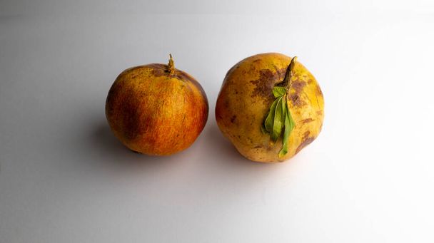 Owoc granatu z łodygą i liśćmi na białym tle i plamami, jakość 4k - Zdjęcie, obraz