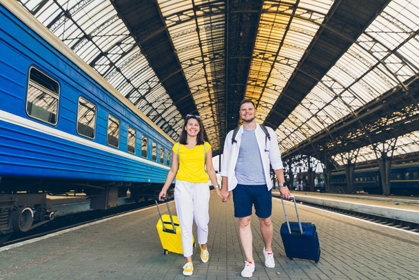 junges Paar läuft mit Koffern auf Rädern durch Bahnhof - Foto, Bild
