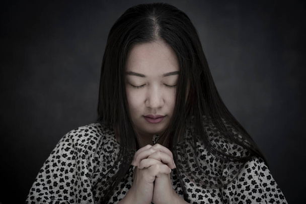 Mulher asiática orando e adorando a DEUS Usando as mãos para orar em crenças religiosas e adorar cristão na igreja ou em locais gerais em fundo branco e preto - Foto, Imagem