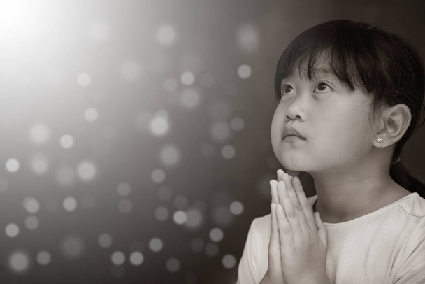 Azjatyckie oblicze Dziecko modlące się i czczące Boga Używając rąk do modlitwy w przekonaniach religijnych i czczenia chrześcijanina w kościele lub w ogólnych miejscach w tle bieli i czerni - Zdjęcie, obraz