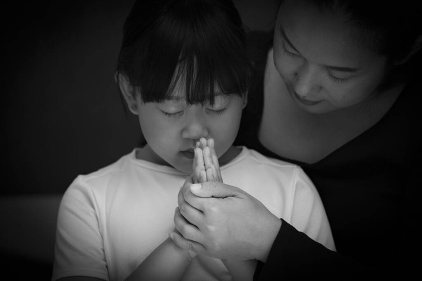 Asian face woman and child praying and worship to GOD Using hands to pray in religious beliefs and worship christian in the church or in general locations in While and Black background - Photo, Image