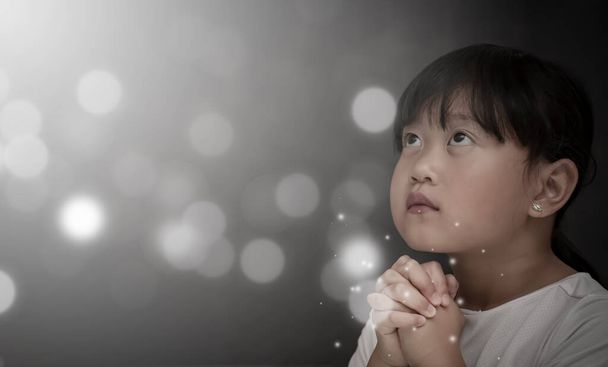 Asian face Child praying and worship to GOD Using hands to pray in religious beliefs and worship christian in the church or in general locations in  White and Black background - Photo, Image