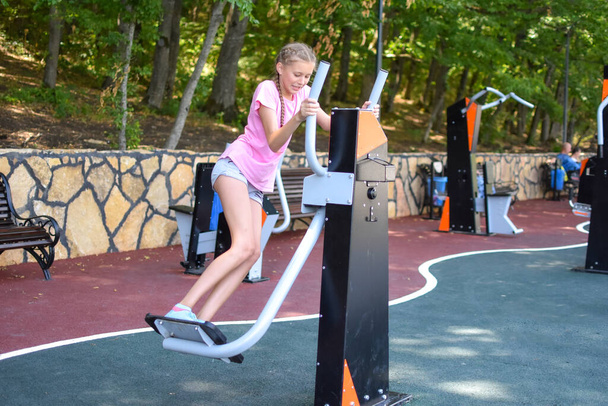Girl on sports field. Teenager girl doing gymnastic exercises at outdoor gym. - Foto, Imagen