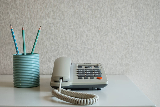 Telefoon en pastel potloden in het blauwe glas op het bureau op grijze muur backgroun - Foto, afbeelding