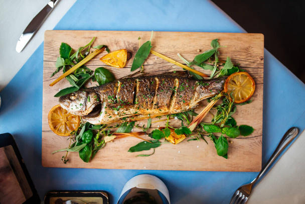 Roasted sea bass with herbs on the wooden board - Photo, Image