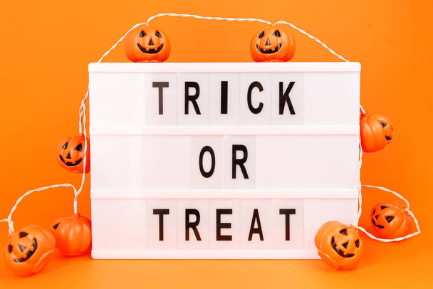 White board with little scary pumpkins on orange background. Halloween theme. - Foto, afbeelding