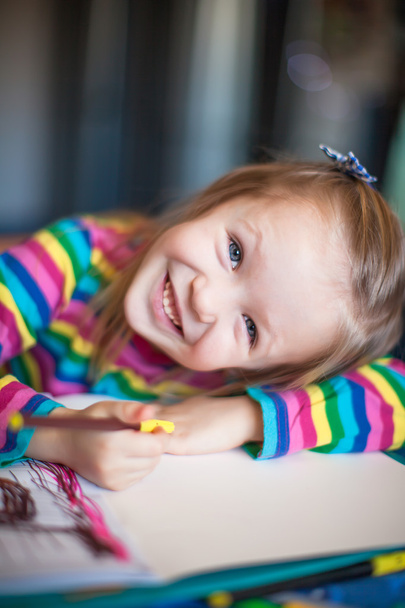 χαριτωμένο κοριτσάκι ζωγραφική με μολύβια, ενώ κάθεται στο τραπέζι της - Φωτογραφία, εικόνα