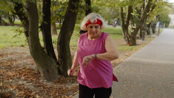 Старшая бегунья тренируется на улице, наслаждается природой. Тренировка по утрам. Здоровый образ жизни - Фото, изображение