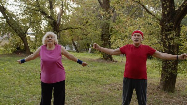 Senior active couple doing sport physical exercises outdoor in city park. Morning stretching workout - Foto, Imagen