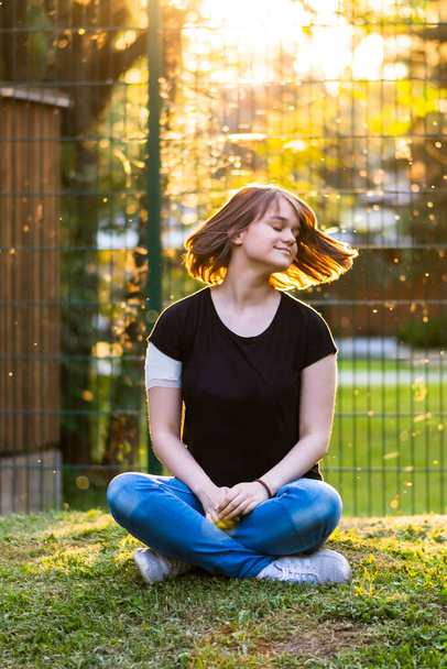 Młoda dziewczyna z nową krótką fryzurę siedzi sam i pozowanie w parku z pięknym naturalnym tle - Zdjęcie, obraz