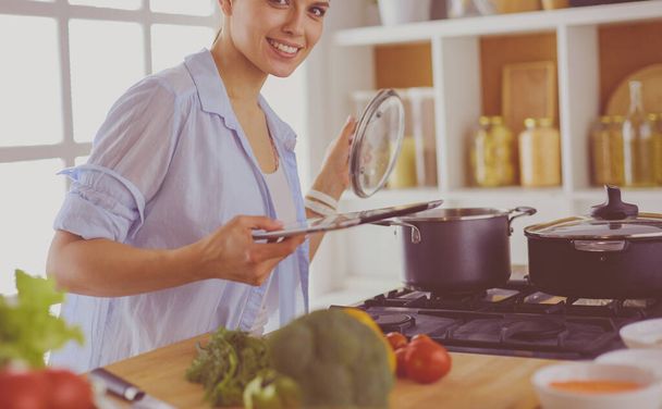 Young woman using a tablet computer to cook in her kitchen. - Photo, Image
