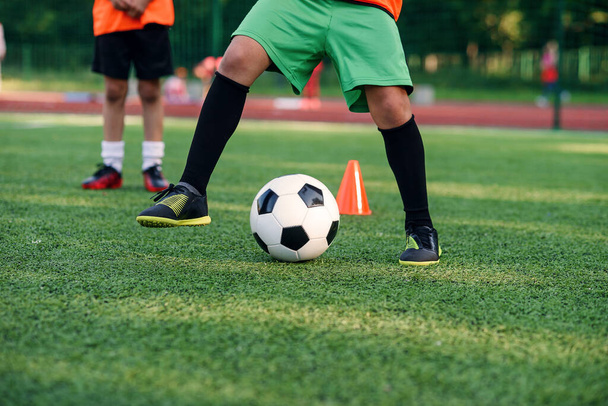 Soccer player kicking ball on field. Soccer players on training session. Close up footballer feet kicking ball on grass. - Photo, image